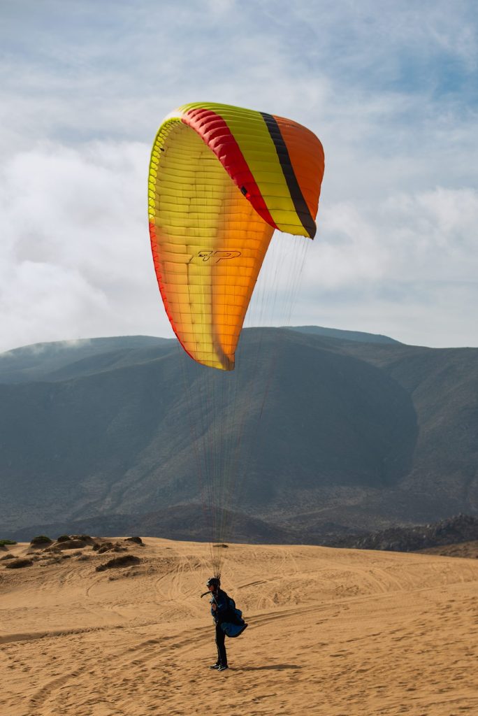 Parapente amarillo elevándose en las dunas