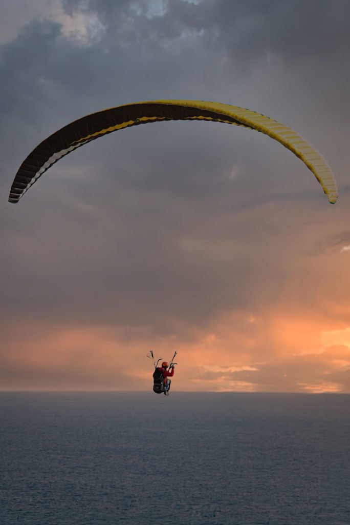Vuelo en parapente al atardecer sobre el mar