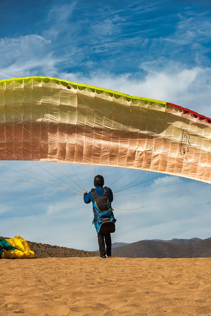 Instructor inflando la vela de parapente en la duna