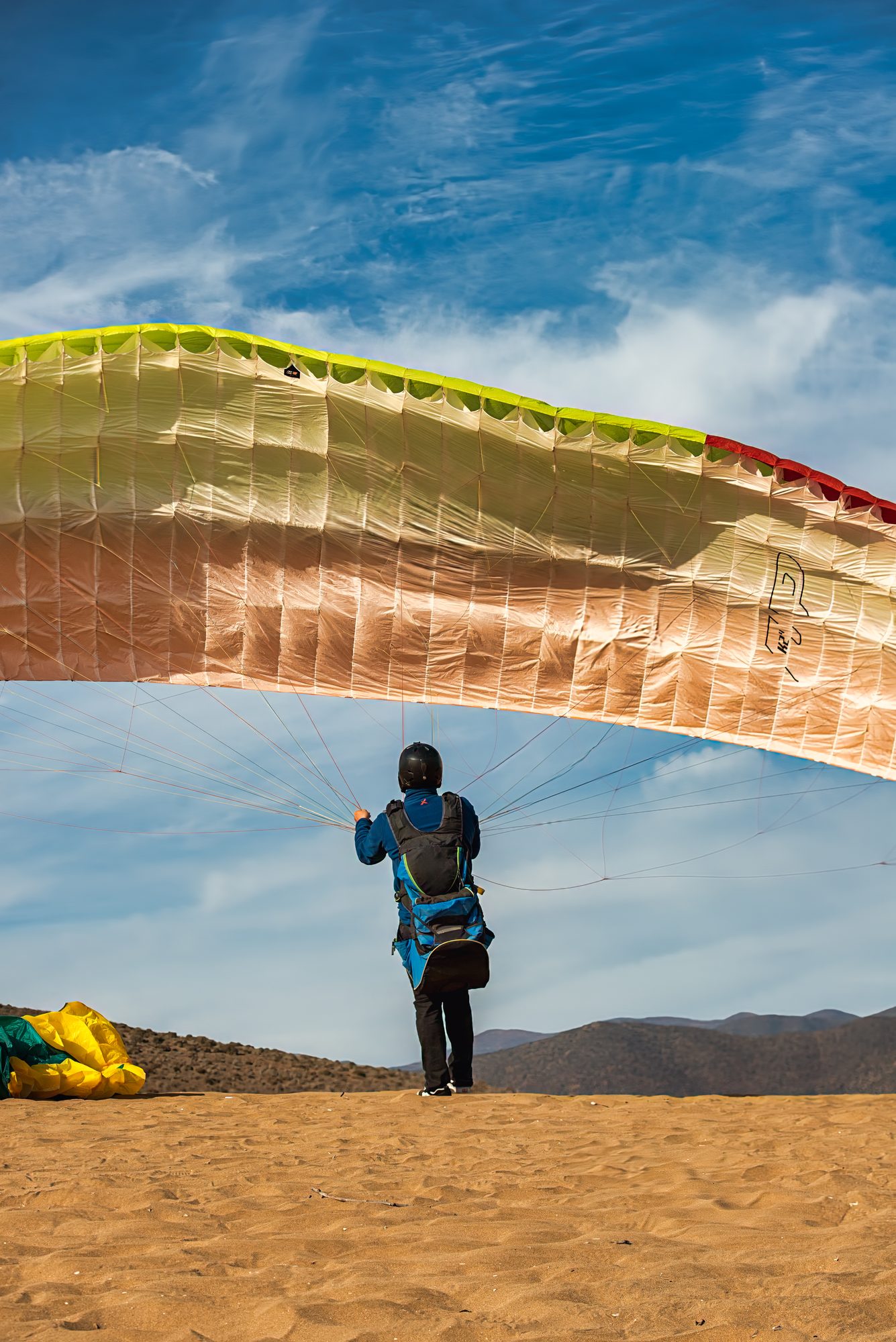 Instructor inflando la vela de parapente en la duna